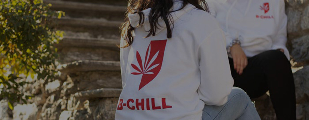 Two girls wearing B-Chill CBD sweatshirts, chilling on a stair in nature